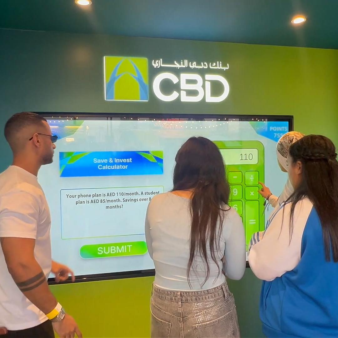 People playing a multi-level interactive financial literacy game at a brand activation event in Dubai, learning how to save and invest money.